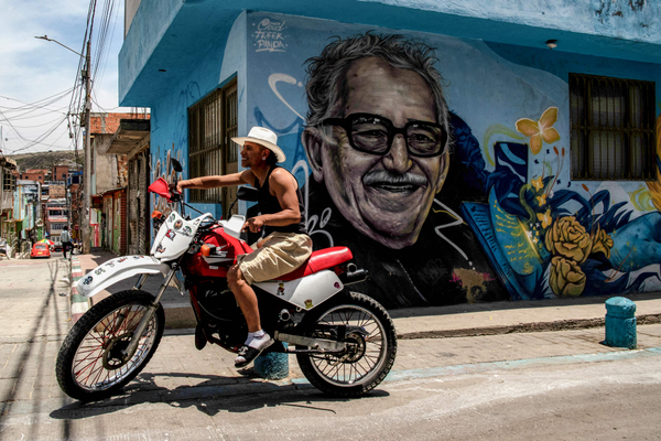 Um motociclista passa em frente ao retrato do escritor colombiano Gabriel García Márquez, num dos murais espalhados pelas ruas de Ciudad Bolívar, em Bogotá