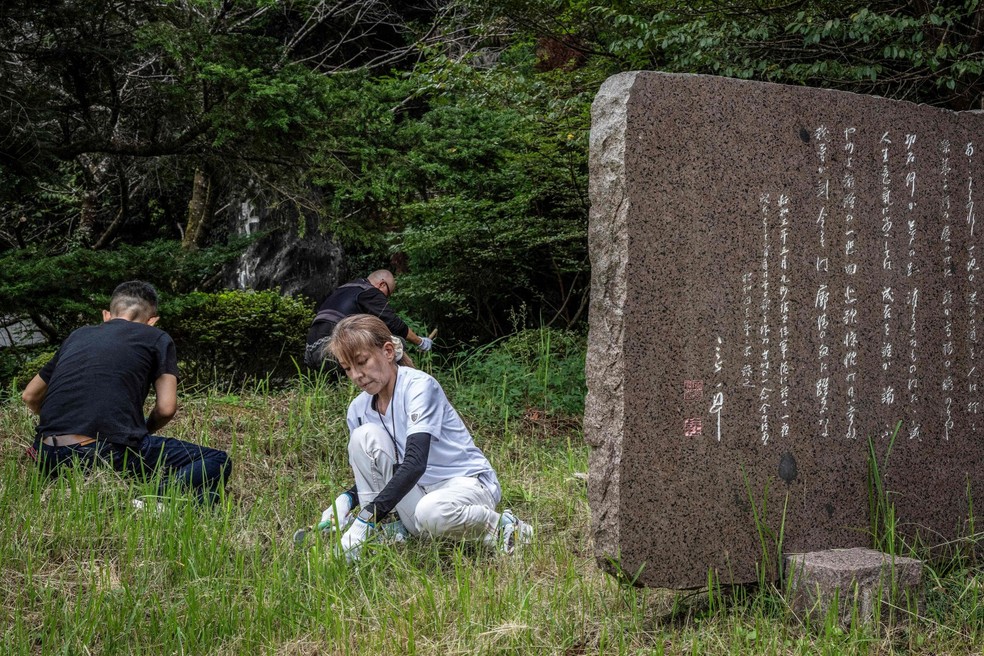 A yakuza aposentada Mako Nishimura retira ervas daninhas durante uma atividade de limpeza com membros de um grupo de direita no santuário Gifu Gokoku, em Gifu, Japão — Foto: Yuichi Yamazaki / AFP