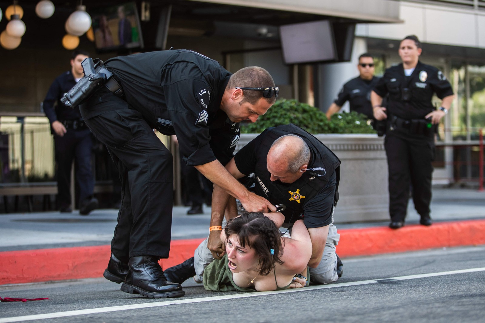 Policial do Serviço Secreto americano imobiliza manifestante no chão depois que ela correu em direção a uma carreata a caminho do Centro de Convenções de Los Angeles, onde os líderes norte e sul-americanos estão reunidos para a nona Cúpula das Américas em Los Angeles, em 8 de junho de 2022 — Foto: Apu GOMES / AFP