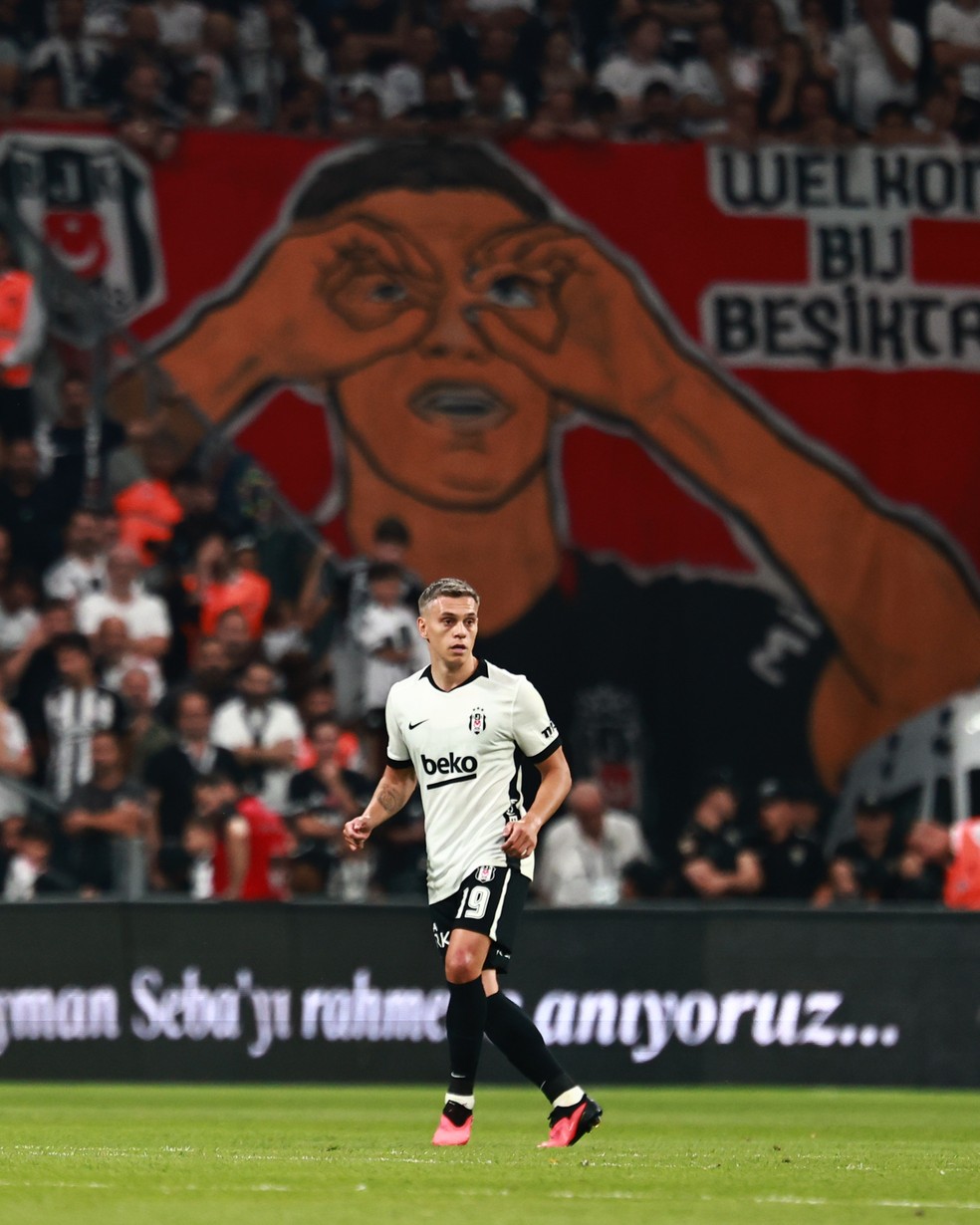 Trossard em campo pelo Besiktas. Ao fundo, bandeira da torcida com a comemoração do jogador — Foto: Divulgação / Besiktas