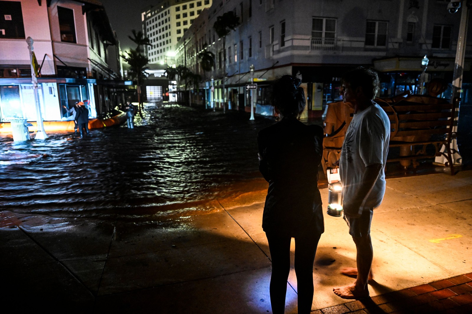 Pessoas observam ruas inundadas depois que o furacão Milton atingiu Fort Myers — Foto: Chandan Khanna/AFP