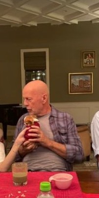 O ator Bruce Willis entre a filha (à esquerda) e a mulher, num jantar em casa: ator segura filhote de cachorro à mesa — Foto: Reprodução/Instagram