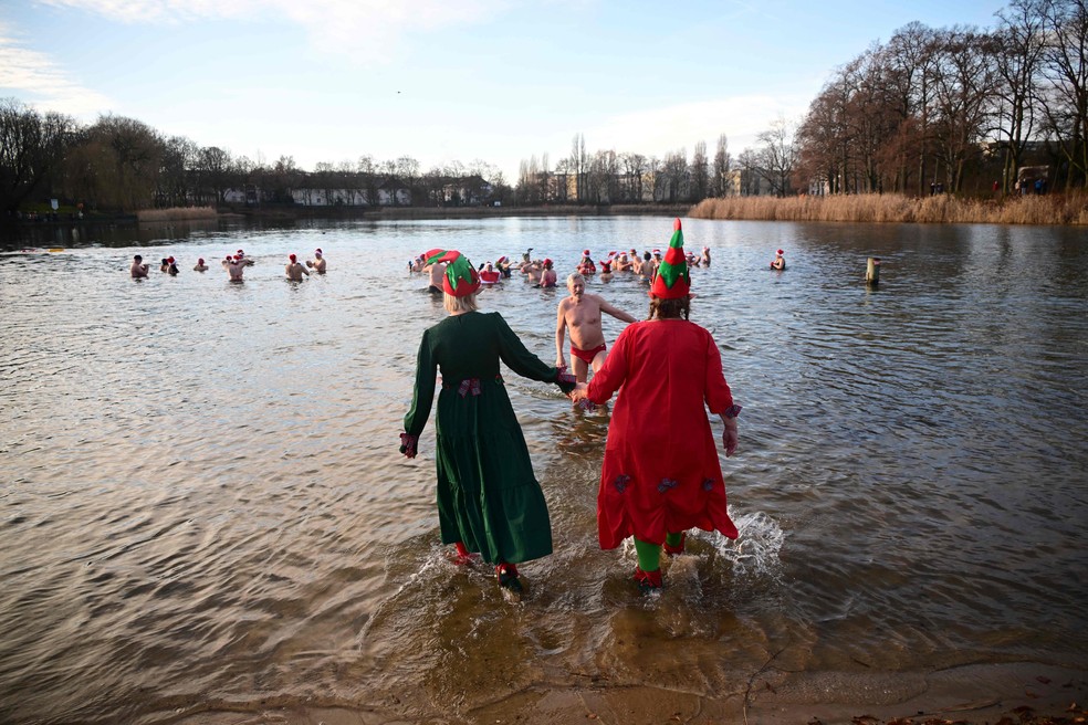 Membros do clube de natação Focas de Berlim se reúnem para a tradicional natação de Natal no Lago Orankesee — Foto: AFP/Tobias Schwarz