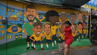 Mulher passa por um mural representando a seleção brasileira de futebol na Copa do Mundo, na favela da Rocinha — Foto: Carl de Souza / AFP