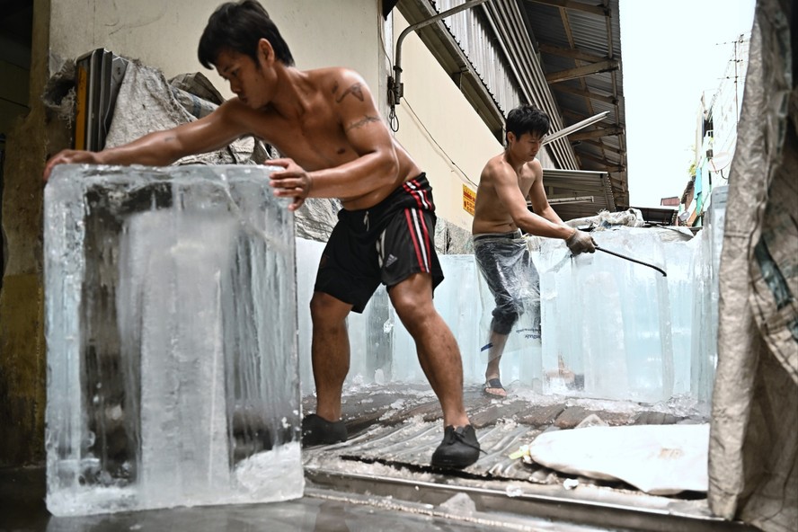 Trabalhadores movem blocos de gelo para uma unidade de armazenamento em um mercado de produtos frescos durante as ondas de calor em Bangkok, Tailândia