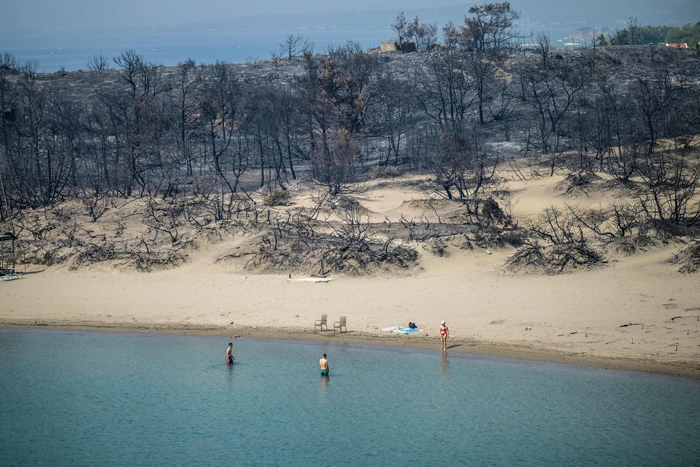Pessoas correram para o mar para fugir de queimadas na Grécia — Foto: Angelos Tzortzinis / AFP