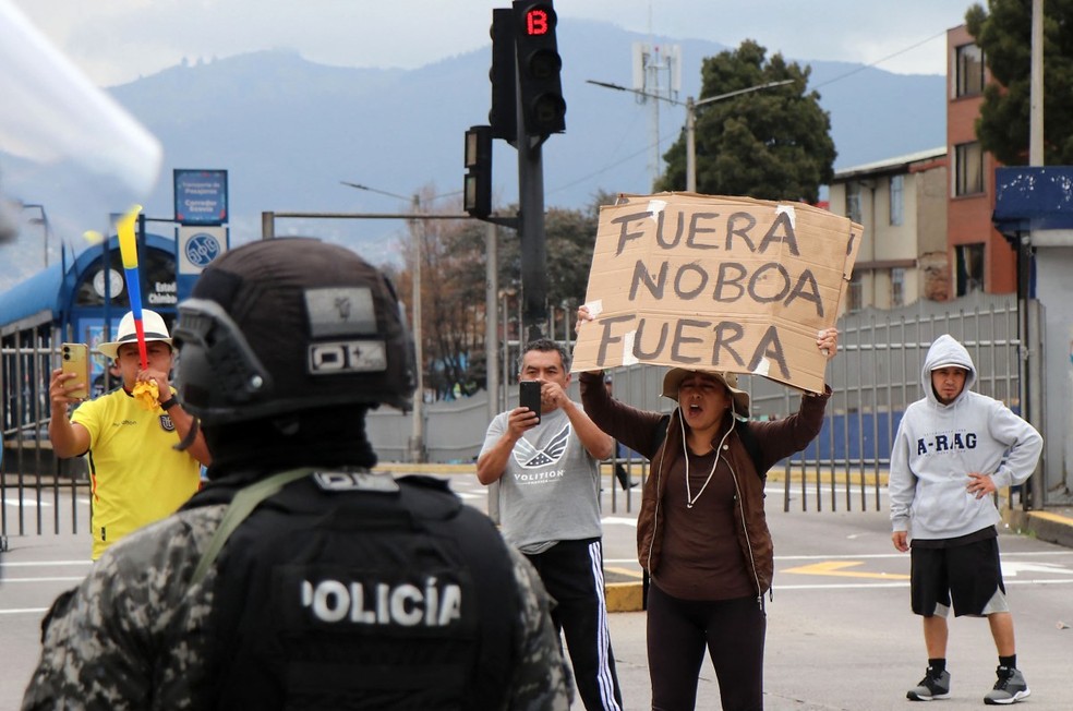 Um manifestante segura uma placa que diz “Fora Noboa” durante uma marcha contra o racismo, a criminalização dos protestos e em apoio à greve nacional convocada pela Conaie, a maior organização indígena do Equador, enquanto se dirigia ao parque El Arbolito, em Quito — Foto: Galo Paguay / AFP