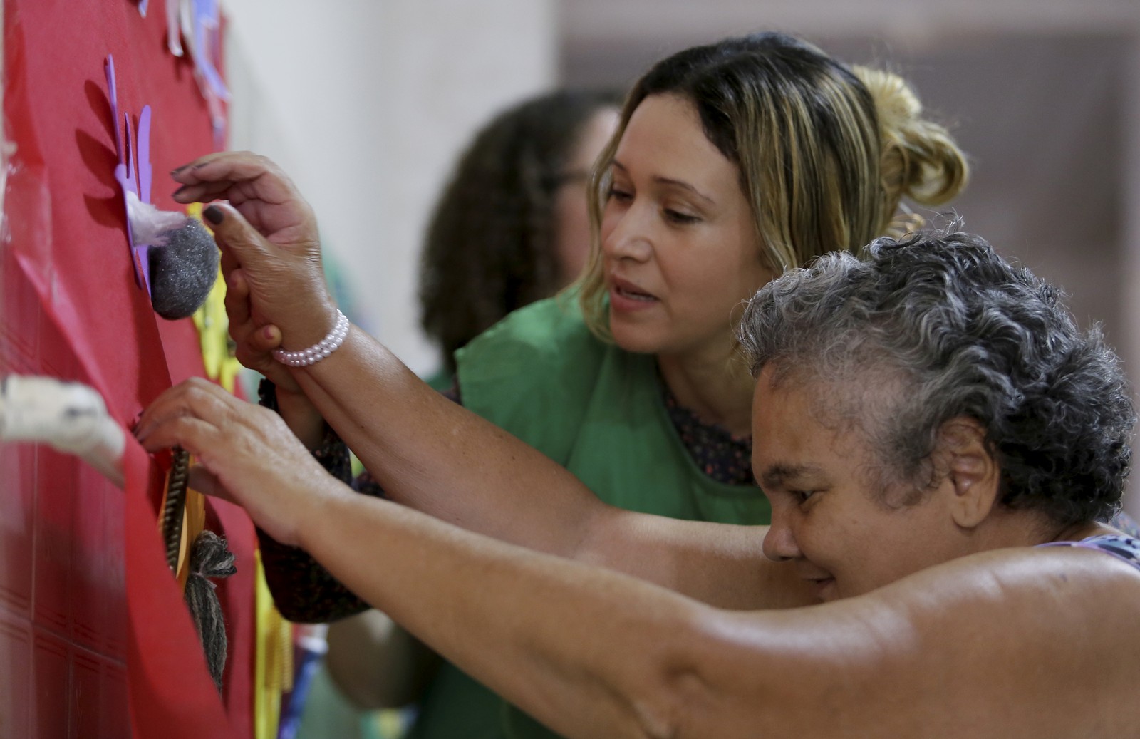 Student Rubi Santos guides an elderly woman in sensory activities — Photo: Marcelo Thebald / Agência O Globo