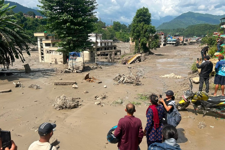 Moradores observam casas parcialmente submersas após inundações repentinas em Trishuli Bazar, no Nepal, em 26 de agosto de 2026