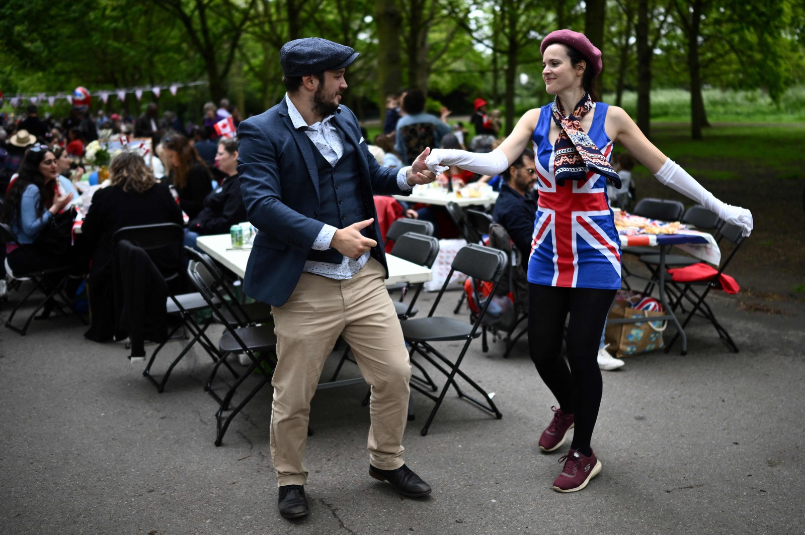 Casal dança no no Regent's Park, no centro de Londres, um dia após coroação de Charles III — Foto: AFP
