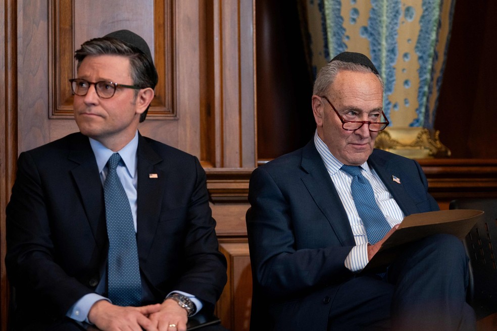 Mike Johnson (E), presidente da Câmara dos EUA, ao lado de Chuck Schumer, líder da maioria democrata no Senado, em cerimônia no Congresso — Foto: Allison ROBBERT / AFP