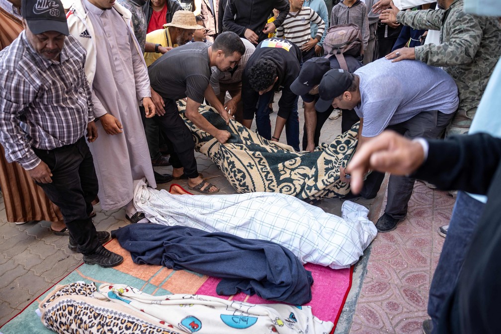  Homens alinham os corpos de pessoas mortas em Moulay Brahim, província de Al Haouz, no sábado passado.  — Foto: Fadel Senna / AFP
