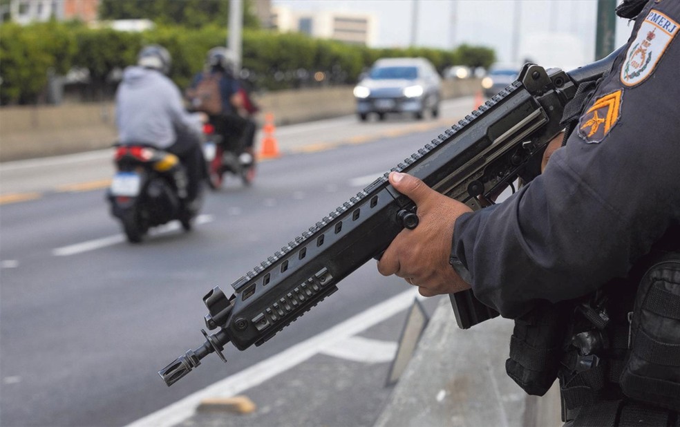 Por toda parte. Policial militar patrulha a Linha Amarela, via expressa que ligar a Ilha do Fundão à Barra, com fuzil em punho — Foto: Márcia Foletto