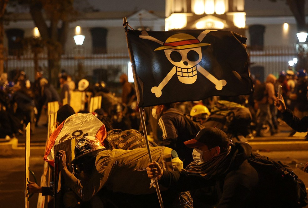 Símbolo do movimento jovem, bandeira com imagem do mangá'One Piece' é levada para confronto com policiais durante protesto contra o presidente interino do Peru, José Jeri, em Lima — Foto: Hugo CUROTTO / AFP