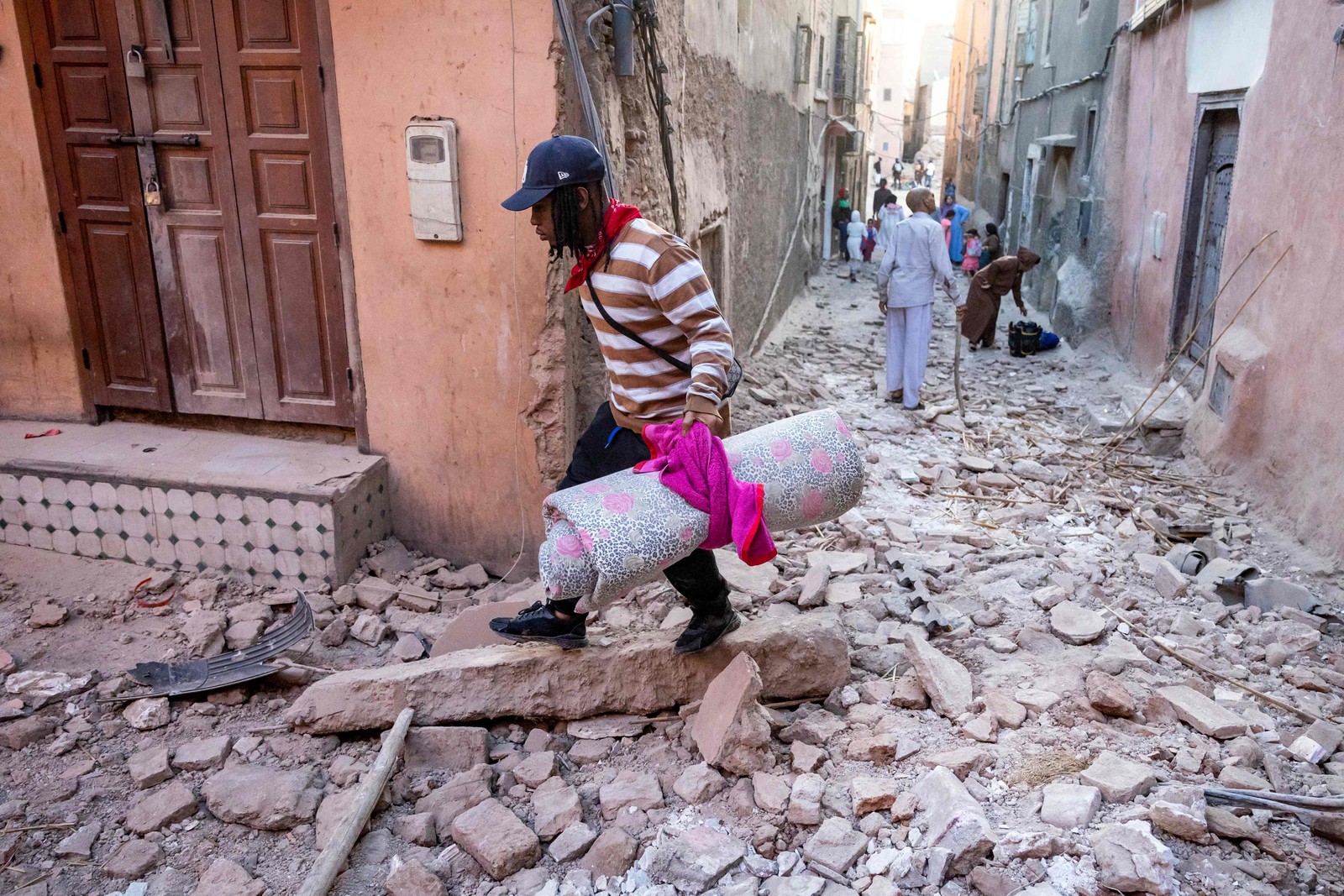 Homem caminha com seus pertences pelos escombros em um beco na cidade velha de Marrakesh, danificada pelo terremoto — Foto: Fadel Senna / AFP