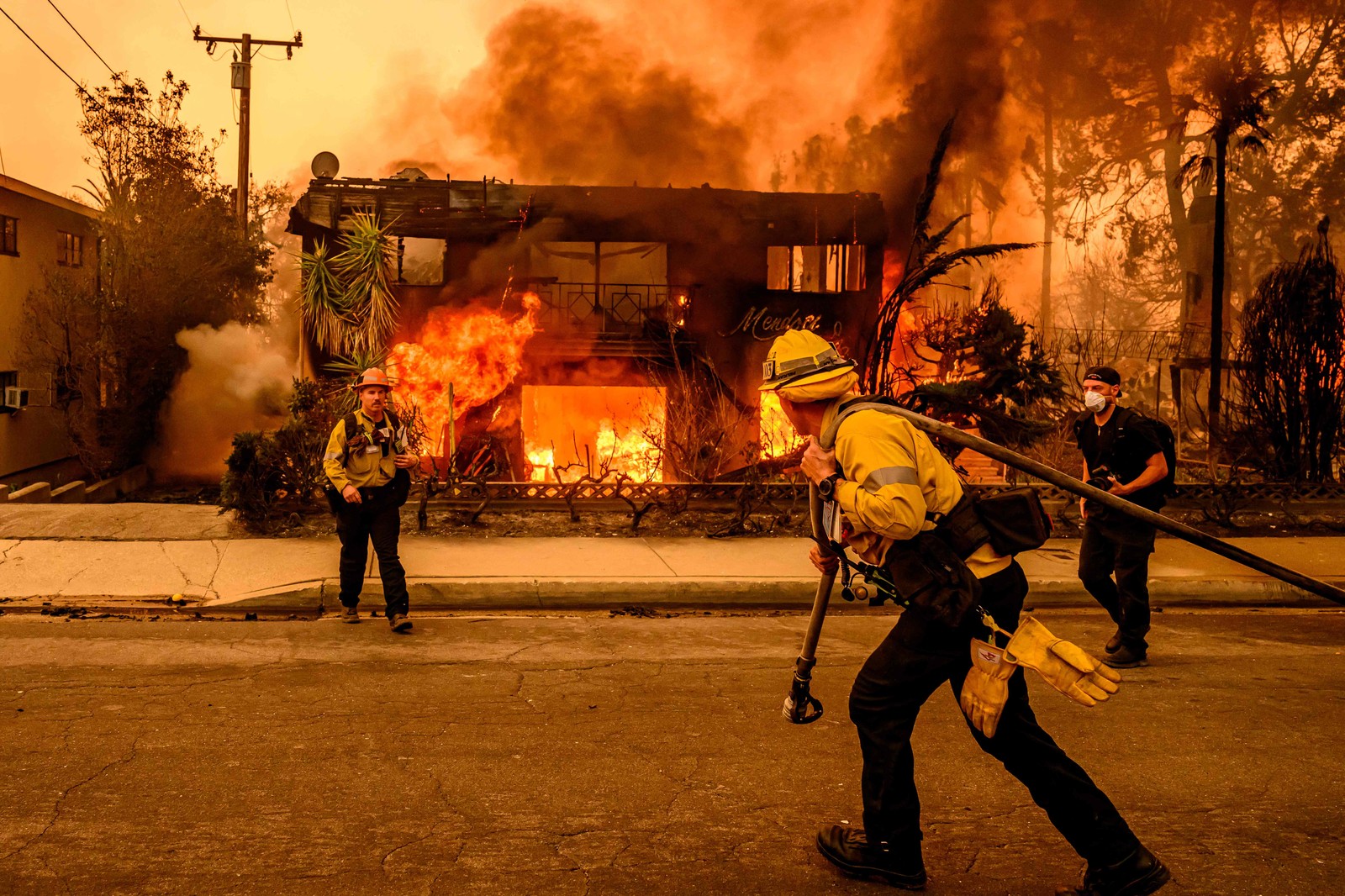 Bombeiros trabalham no local enquanto um prédio de apartamentos queima durante o incêndio em Eaton, na área de Altadena, no condado de Los Angeles, Califórnia — Foto: JOSH EDELSON / AFP