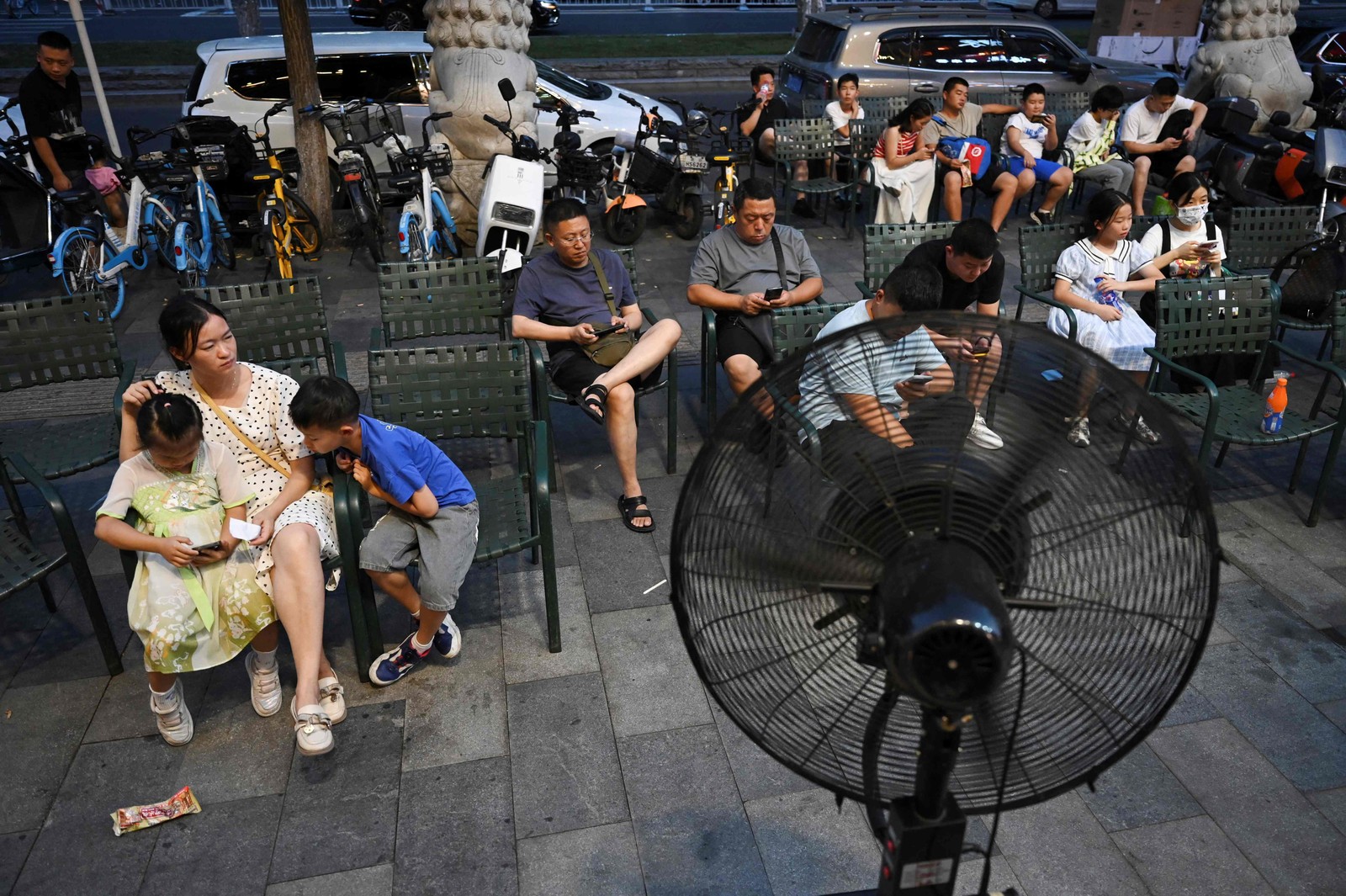Pessoas esperam na frente de um ventilador em Beijing, na China, em julho de 2023 — Foto: GREG BAKER