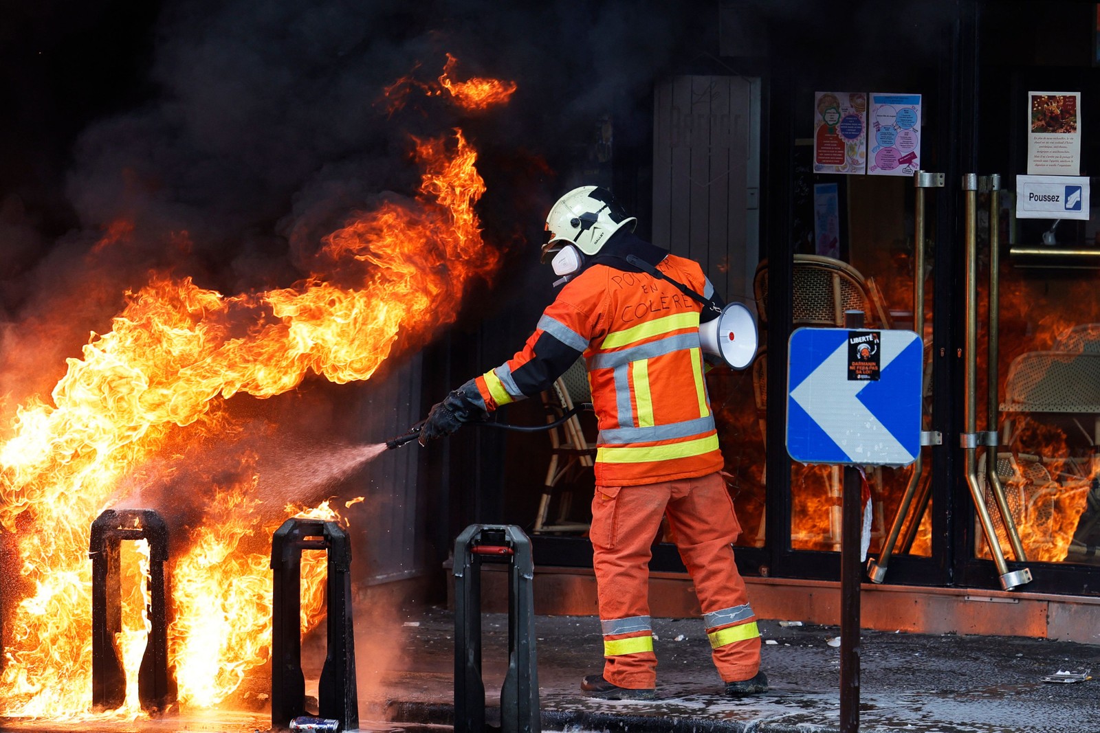 Um bombeiro, que participava do protesto, apaga um incêndio numa estação bicicletas em Paris — Foto: Geoffroy VAN DER HASSELT / AFP