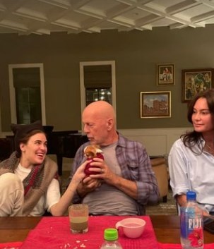O ator Bruce Willis entre a filha (à esquerda) e a mulher, num jantar em casa: ator segura filhote de cachorro à mesa — Foto: Reprodução/Instagram