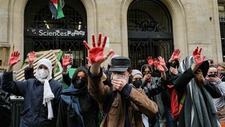 Os manifestantes levantam as mãos cobertas de tinta vermelha para simbolizar o sangue enquanto participam de uma manifestação em frente ao Instituto de Estudos Políticos (Sciences Po Paris) ocupado por estudantes, em apoio aos palestinos, em Paris — Foto: Dimitar DILKOFF / AFP