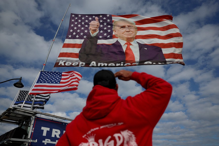 Apoiador de Trump saúda bandeira do ex-presidente hasteada perto de sua casa em Mar-a-Lago, Flórida