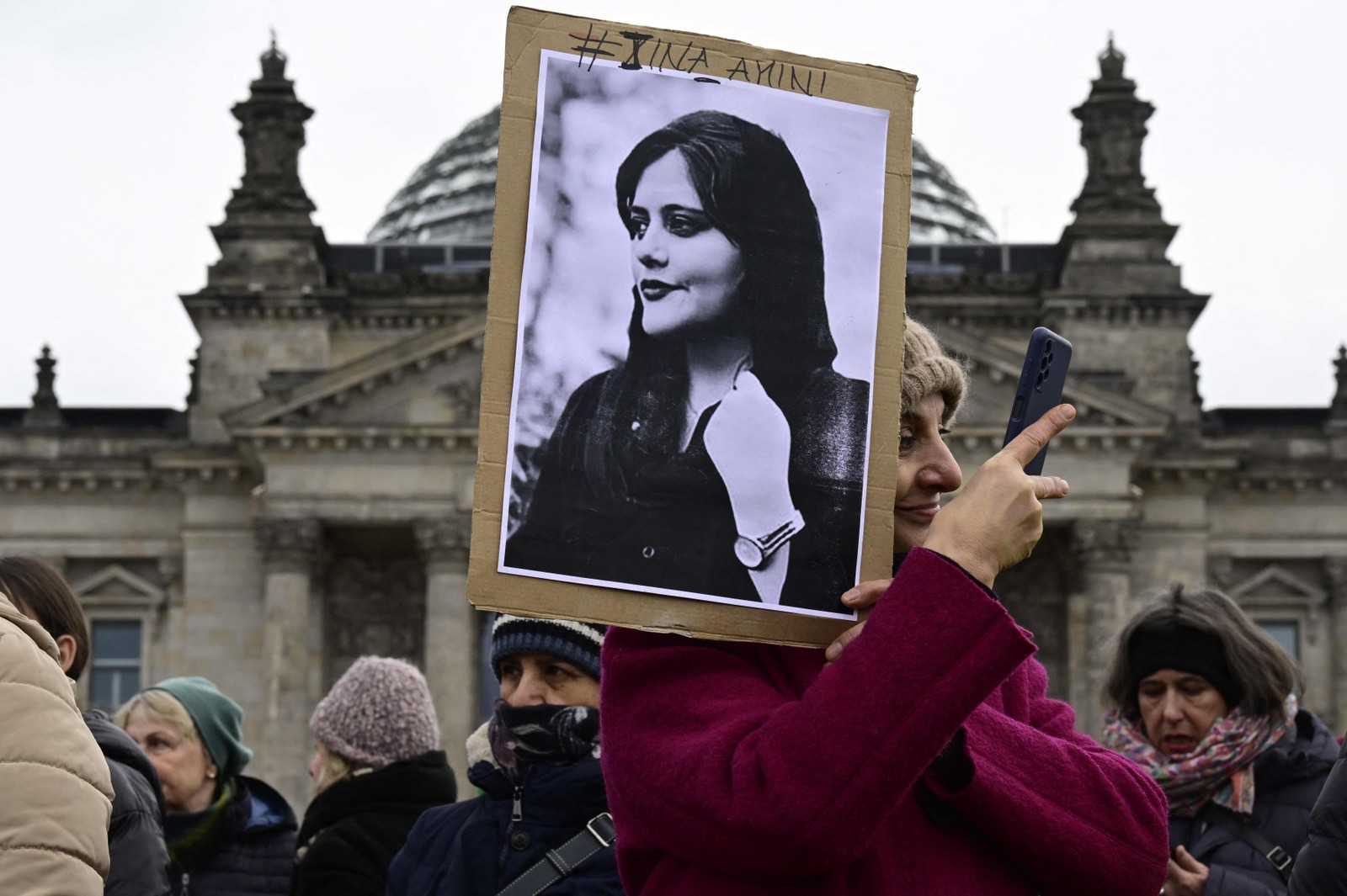 Cartaz com o retrato de Mahsa Amini, jovem iraniana que morreu após ser presa em Teerã pela polícia moral da República Islâmica, aparece em manifestação em frente à câmara baixa do parlamento alemão (Bundestag), em Berlim, pelo Dia Internacional da Mulher, em 2023. John Macdougall / AFP