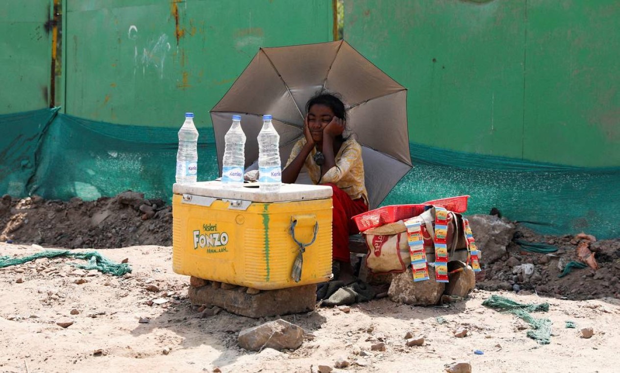 Vendedora água usa um guarda-chuva para se proteger do sol em Nova Délhi. Desde 2010, as ondas de calor mataram mais de 6,5 mil pessoas na Índia  — Foto: ANUSHREE FADNAVIS / REUTERS