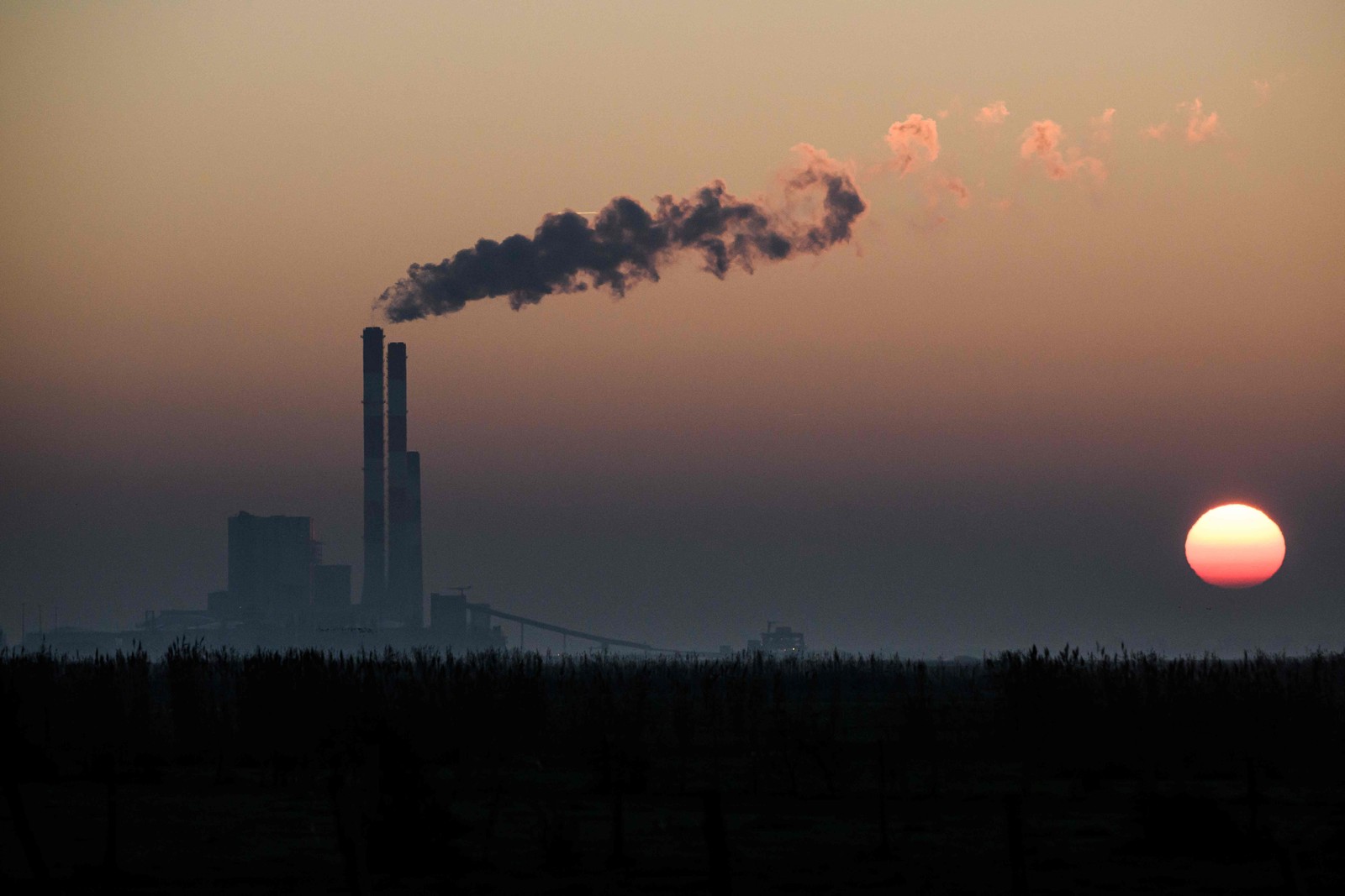 Sol nasce sobre a usina de Cordemais, uma das duas últimas usinas a carvão em serviço na França, em Lavau-sur-Loire — Foto: LOIC VENANCE/AFP