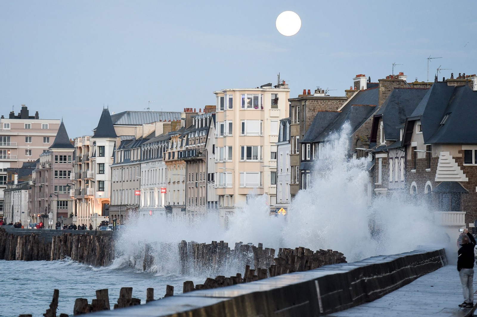 Onda quebra nas docas em Saint-Malo, na França, enquanto a lua nasce no céu ainda claro — Foto: SEBASTIEN SALOM-GOMIS/AFP
