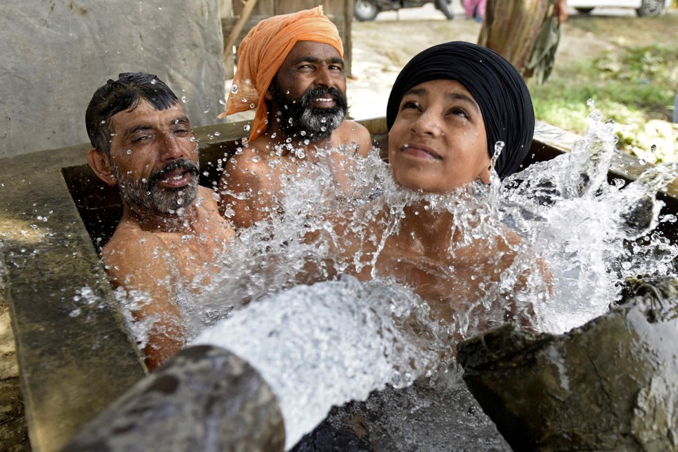 Agricultores se refrescam em um poço nos arredores de Amritsar neste domingo — Foto: Narinder NANU / AFP