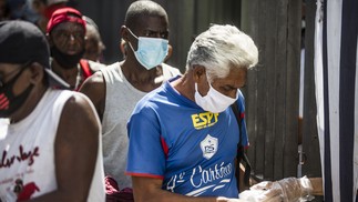 Homem usando máscara de proteção recebe refeição no Centro do RioAgência O Globo