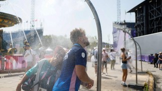 Público se refresca das altas temperaturas em chuveiros — Foto: Odd ANDERSEN / AFP