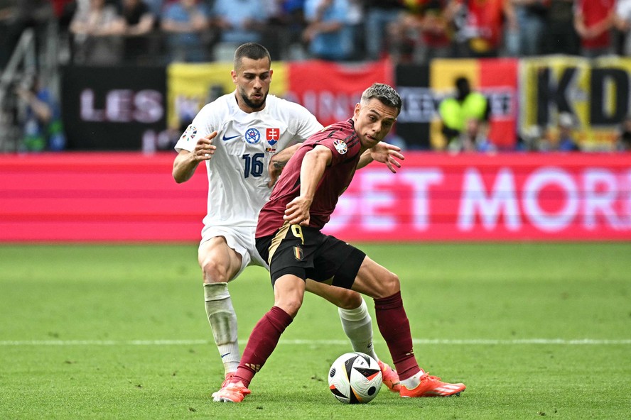 O zagueiro nº 16 da Eslováquia, David Hancko , luta pela bola com o meio-campista belga nº 09 Leandro Trossard durante a partida de futebol do Grupo E da UEFA Euro 2024 entre Bélgica e Eslováquia na Arena Frankfurt. Partida termina 1x0 para a Eslováquia.