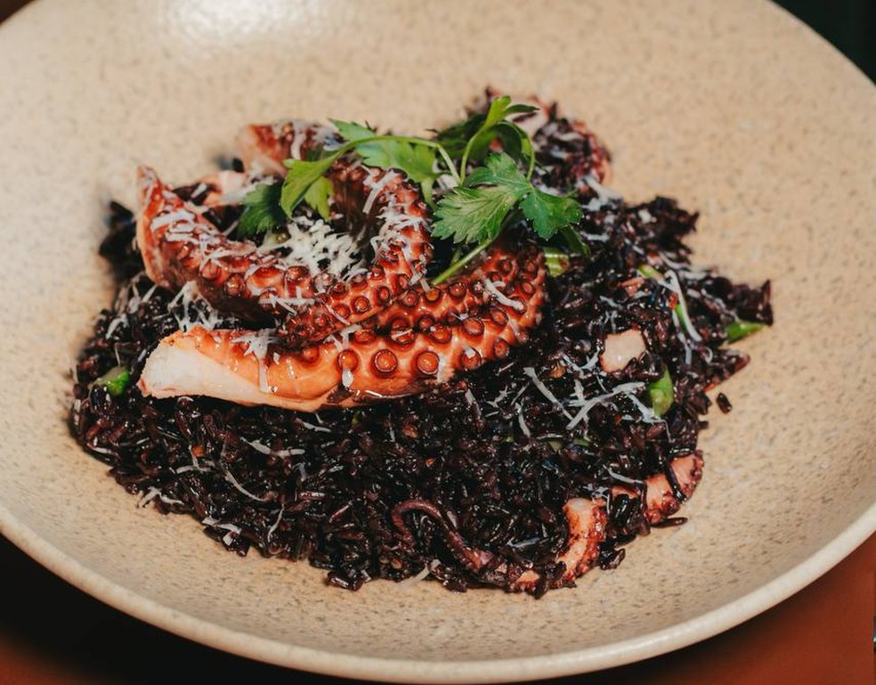 O risoto de arroz negro e polvo com aspargos faz parte do festival dedicado ao prato no Origens, restaurante do Hotel Radisson — Foto: Divulgação