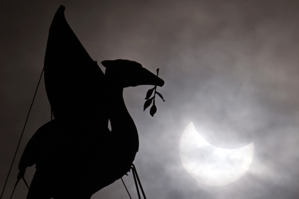 A lua passa na frente do sol durante um eclipse solar parcial atrás da estátua Liver Bird no topo do The Royal Liver Building, na orla de Liverpool — Foto: Foto de Paul ELLIS / AFP