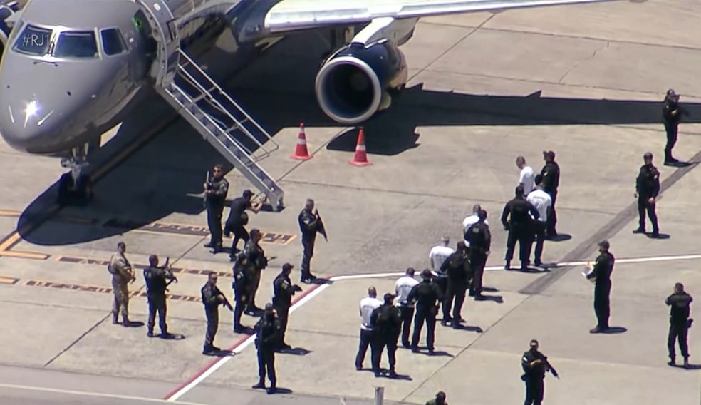 Presos a caminho da aeronave que os levará para presídios federais — Foto: Reprodução / TV Globo