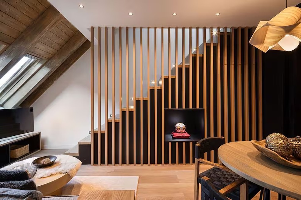 O espaço de estar da Suíte Messi, com área de estar, iluminação natural e acabamentos em madeira — Foto: Reprodução