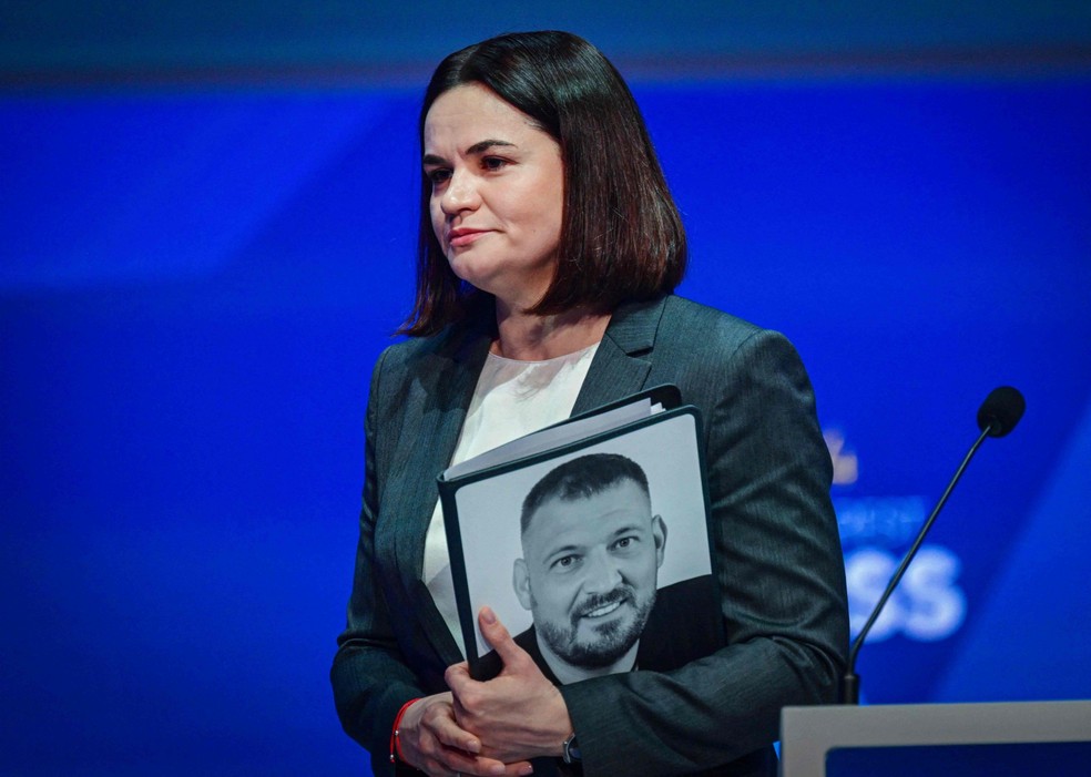 A líder da oposição bielorrussa, Svetlana Tikhanovskaya, segura uma foto do seu marido, Sergei Tikhanovsky, após se dirigir ao público no início do Congresso do Partido Popular Europeu (PPE) em Bucareste, Romênia — Foto: AFP
