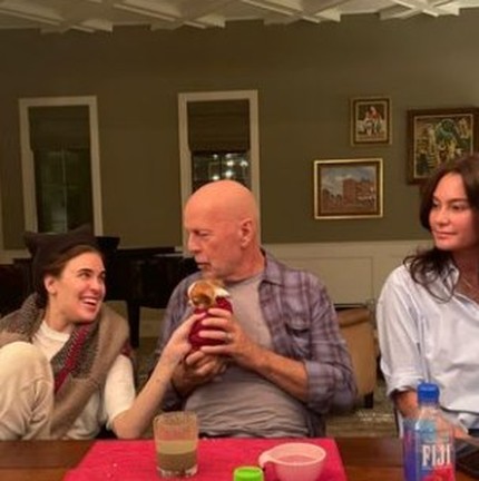 O ator Bruce Willis entre a filha (à esquerda) e a mulher, num jantar em casa: ator segura filhote de cachorro à mesa — Foto: Reprodução/Instagram