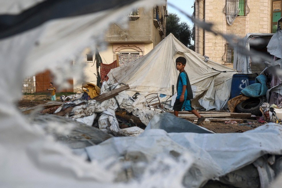 Criança palestina anda em meio a destroços após bombardeio israelense no campo de refugiados de Bureij, em Gaza — Foto: Eyad Baba/AFP