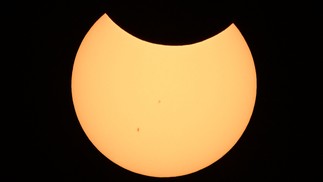 Sol começando a ser tapado pela Lua durante eclipse solar — Foto: Patrick T. Fallon / AFP