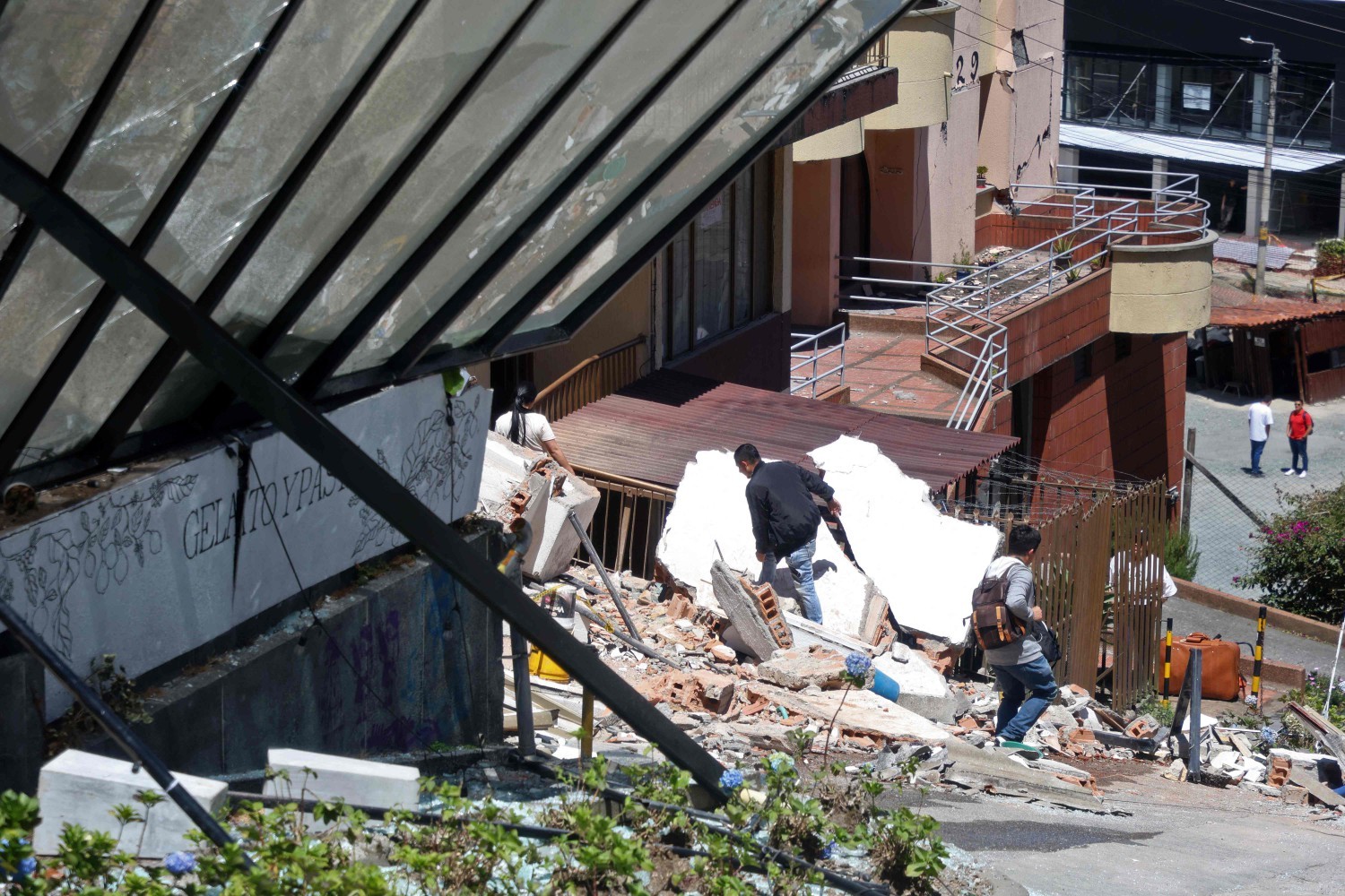 Pessoas caminham entre os escombros após um terremoto em Manizales, Colômbia. — Foto: Giovanny Galvez / AFP