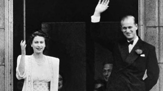 A princesa Elizabeth II e o príncipe Philip, duque de Edimburgo, acenam para a multidão da varanda do Palácio de Buckingham, em Londres, em 1947  — Foto: Arquivo / AFP