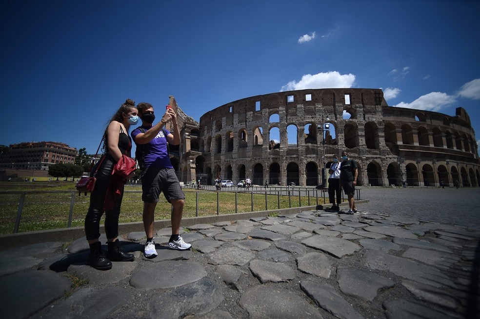 Pessoas posam em frente ao Coliseu, em Roma, a atração turística mais visitada da Itália  — Foto: AFP