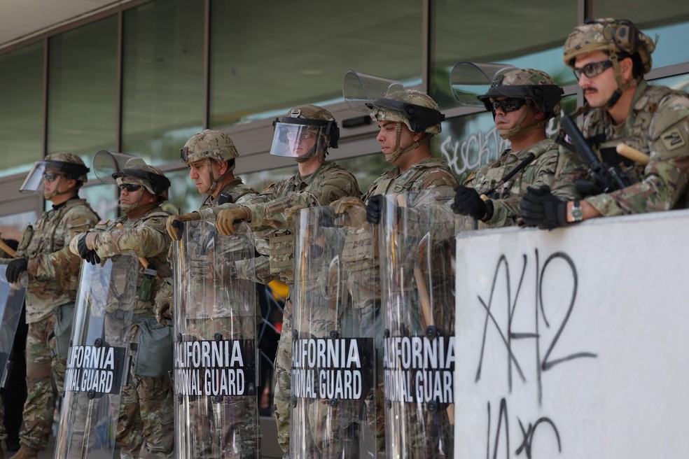 Membros da Guarda Nacional posicionados diante de um prédio federal em Los Angeles — Foto: Patrick T. Fallon / AFP