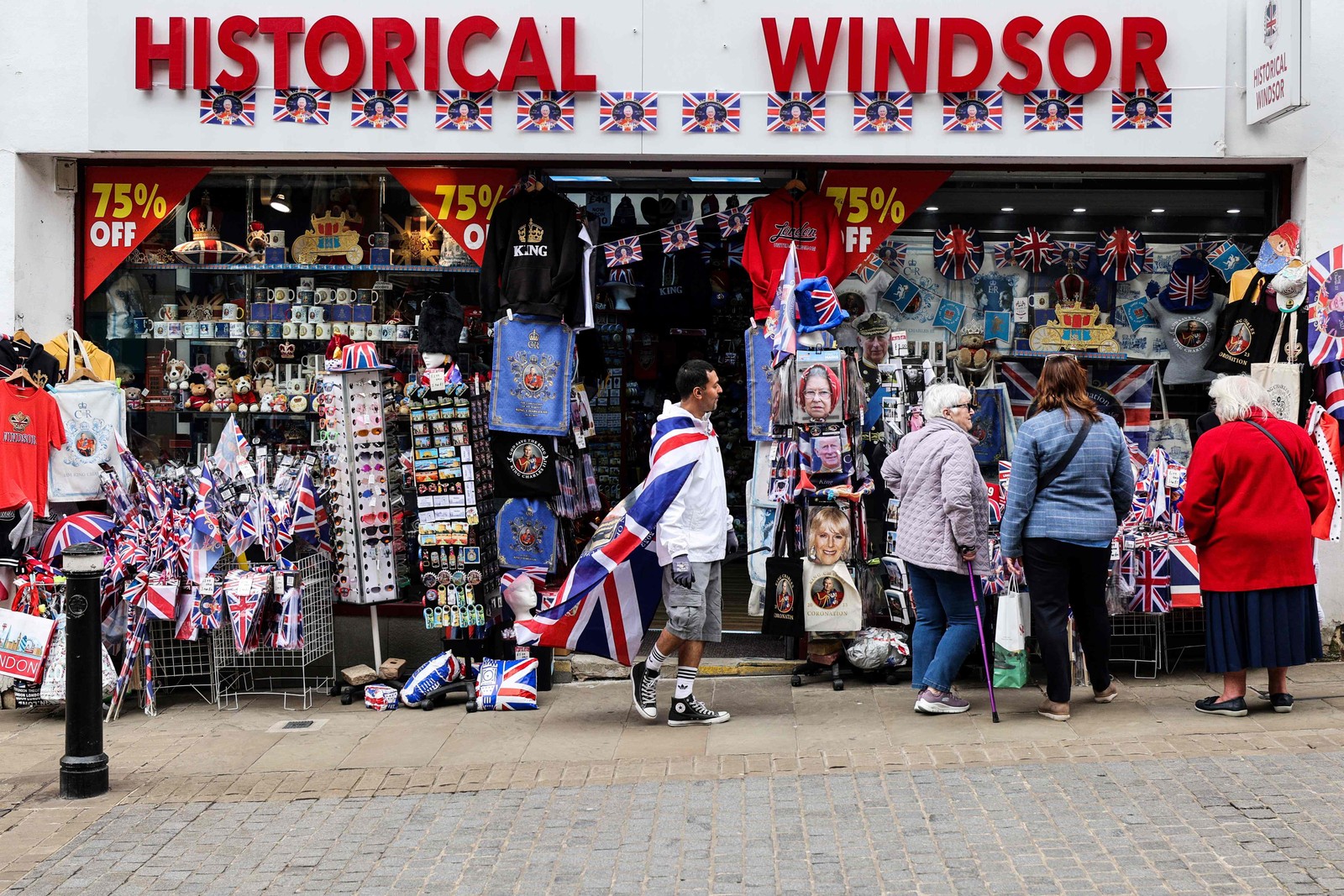 Pessoas olham uma loja que vende lembranças da realeza, em Windsor, em 2 de maio de 2023 — Foto: Adrian DENNIS / AFP