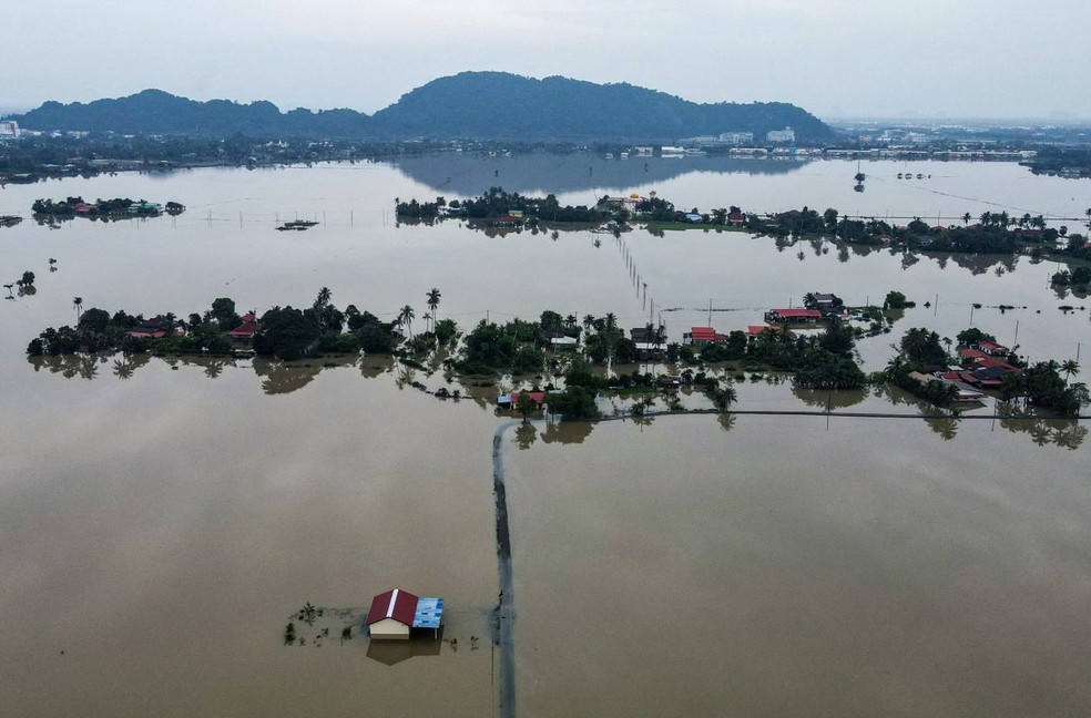 Vista aérea mostra casas cercadas por águas da enchente em Kangar, no estado de Perlis, norte da Malásia, em 28 de novembro de 2025 — Foto: MOHD RASFAN / AFP