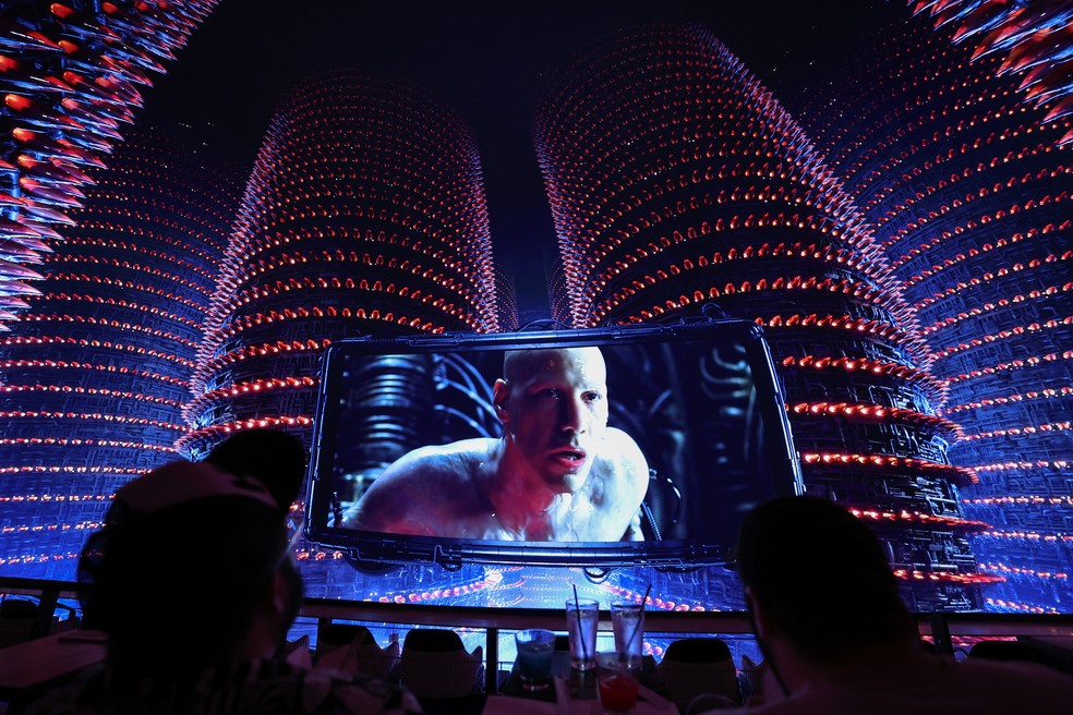 O personagem Neo aparece na tela com uma exibição estendida das torres da usina durante a primeira exibição de realidade compartilhada do filme "Matrix" — Foto: Patrick T. Fallon / AFP