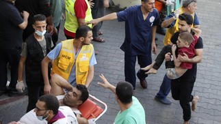 Um homem carrega uma criança ferida para o hospital Al-Shifa, em Gaza, após os ataques israelenses no enclave costeiro na terça-feira — Foto: Mohammed Abed / AFP