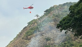 Com drones e helicópteros, bombeiros combatem incêndio provocado por balão em área de preservação em Niterói
